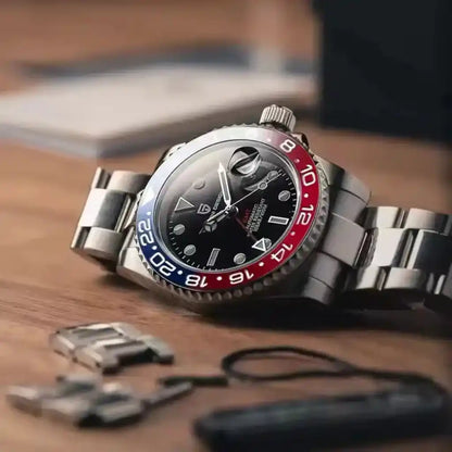 Relógio Automático Masculino Kronos Blue Red deitado sobre mesa de madeira destacando o design bicolor e a pulseira de aço inoxidável